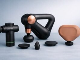 Three massage guns — Hypervolt Go 3, Theragun Sense, and Theragun Mini — arranged on a cool grey-blue studio table with a soft gradient background