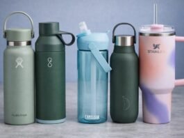 Five reusable water bottles — Hydro Flask, Ocean Bottle, CamelBak, Stanley, and Chilly’s — arranged neatly on a kitchen worktop with a tiled backsplash